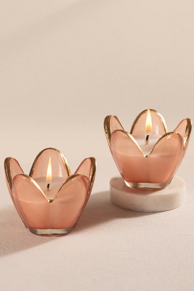 Hand lighting a candle in a rose gold holder on a beige background