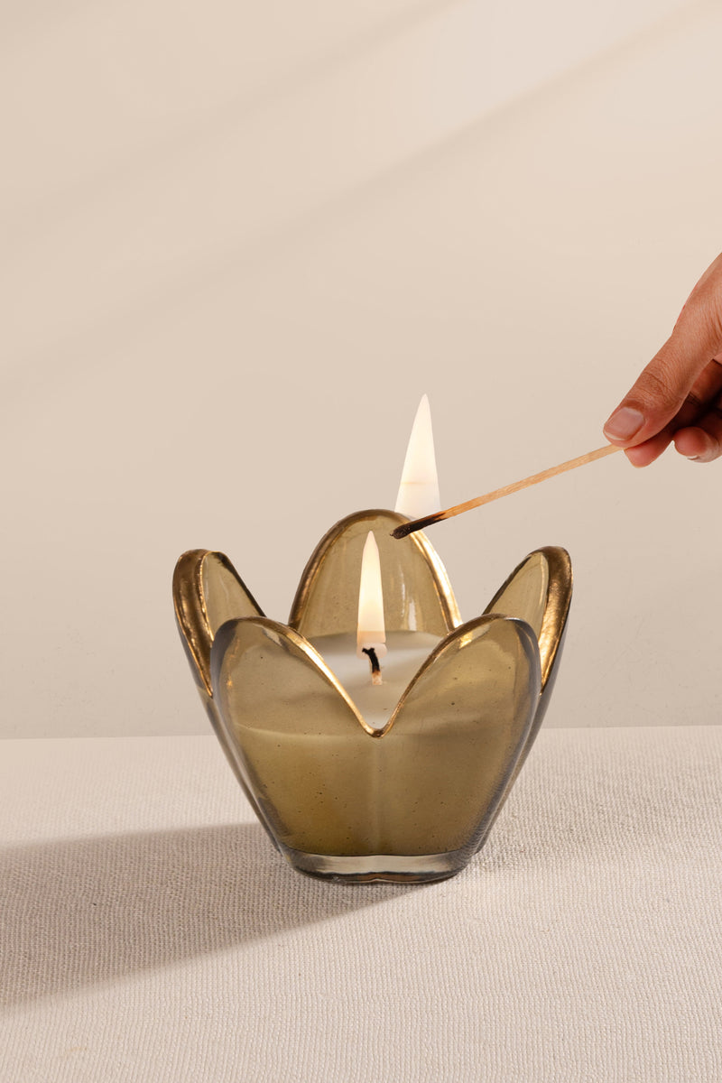 Hand lighting a candle in a decorative flower glass candle