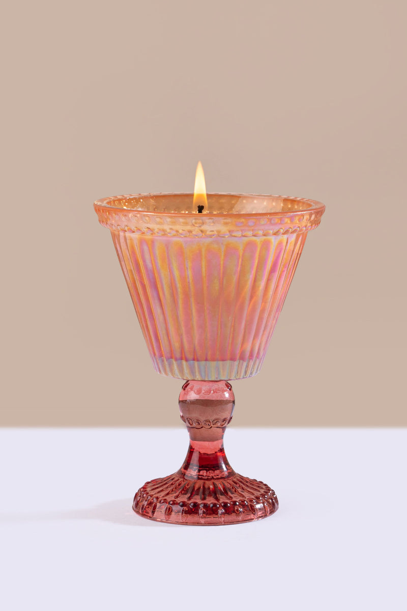  pink candle holder with a lit candle on a beige background