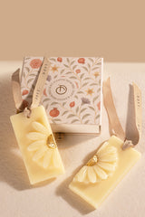 Two floral scented wax tablets with a decorative box on a beige surface
